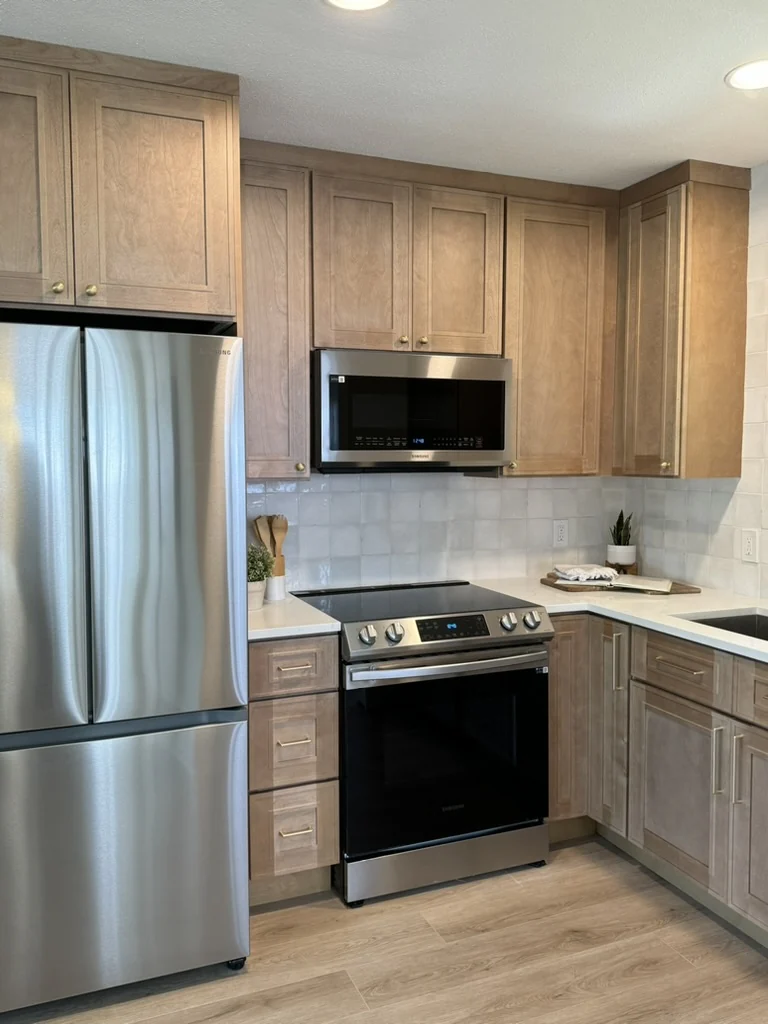 Completed natural wood kitchen with stainless appliances and tiled backsplash