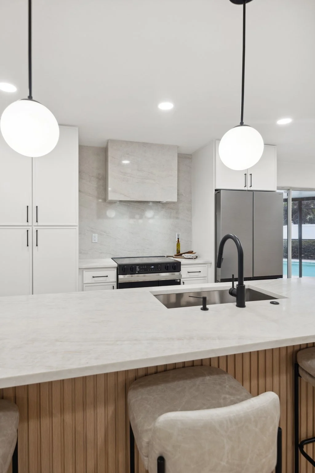 Completed white kitchen with fluted oak island and globe pendants