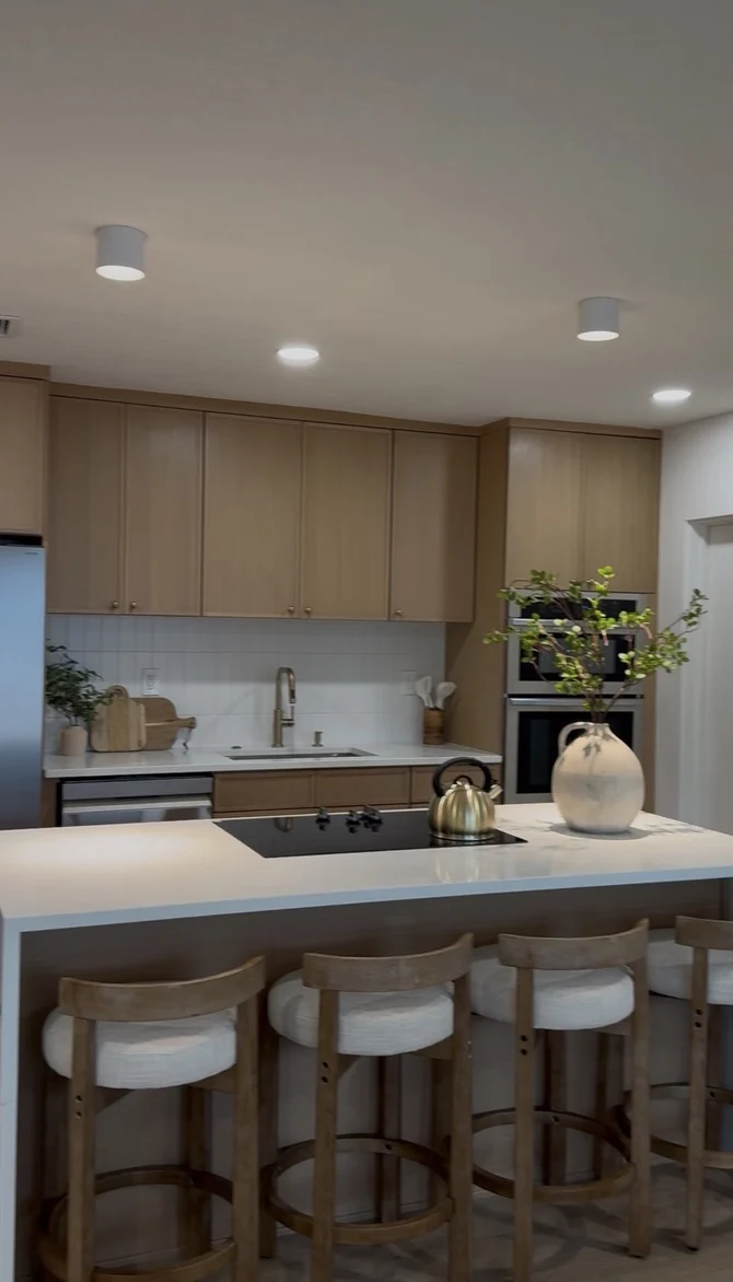 Completed warm wood kitchen with island seating and styled countertop